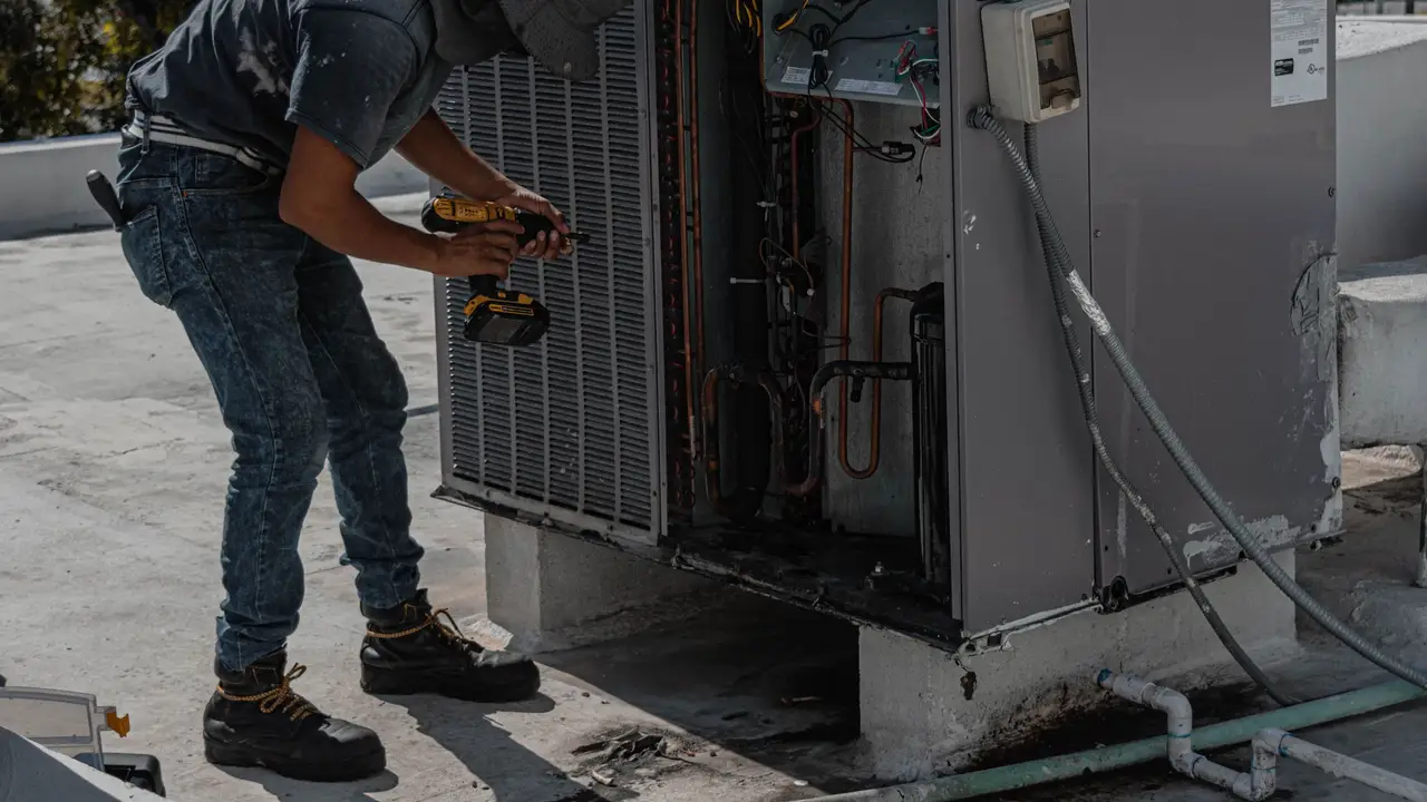 Technician checking refrigerant pressures on a rooftop condenser unit