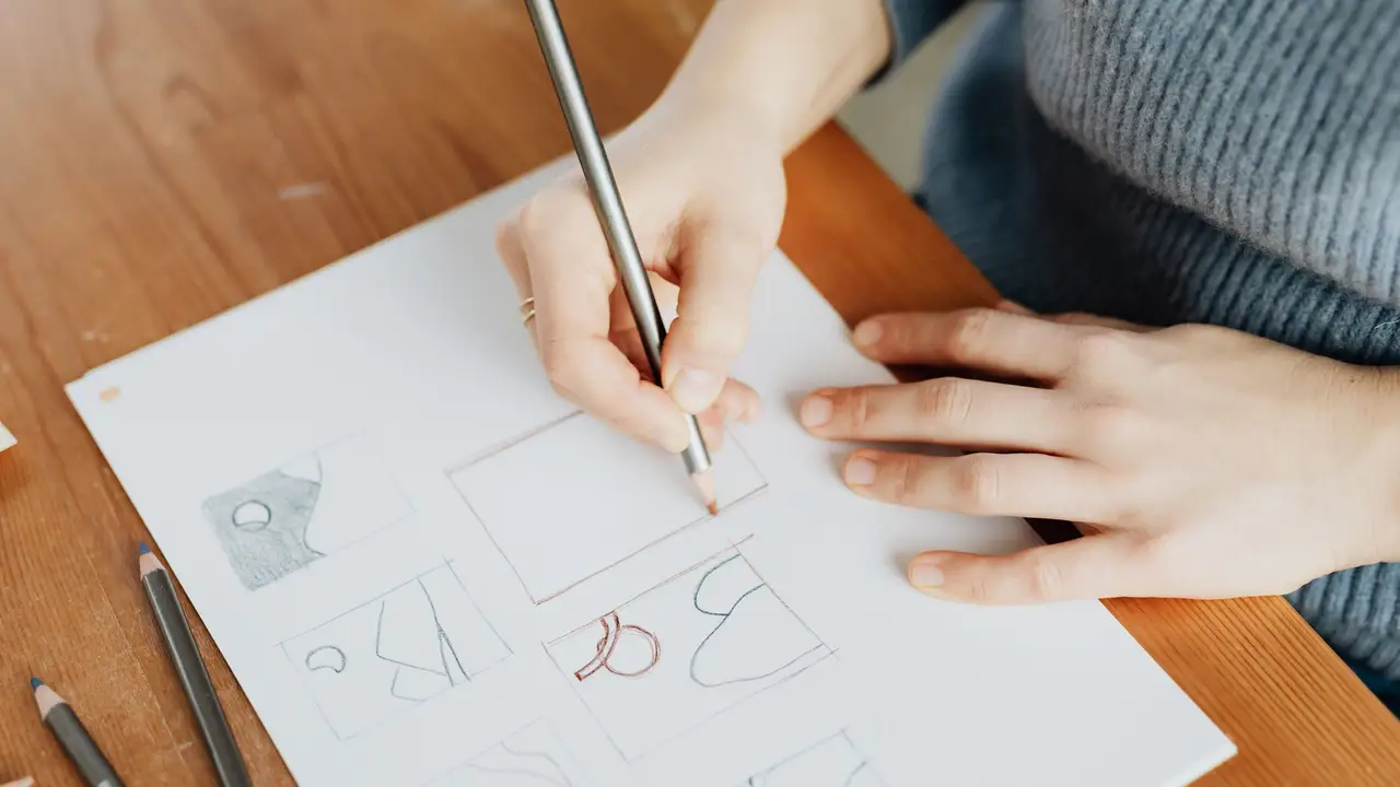 Illustrator drawing at a desk with pencils and paper