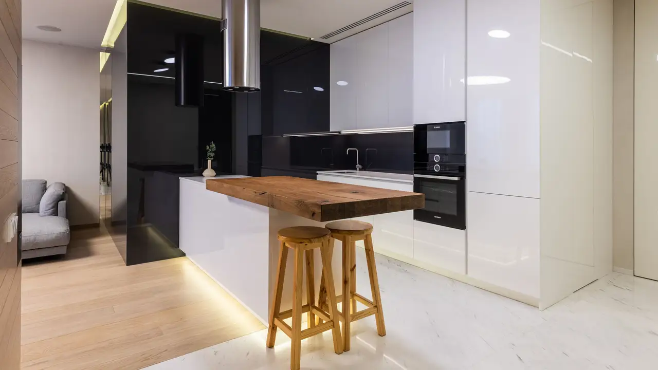 Compact modern kitchen with light oak cabinets and a quartz backsplash
