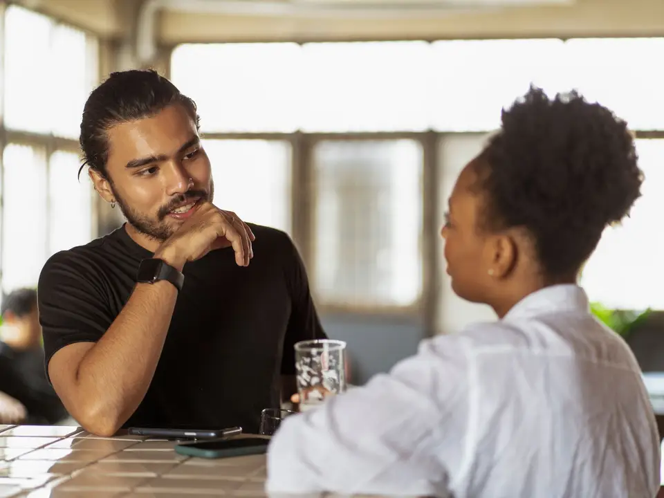 Two adults conversing at a table indoors