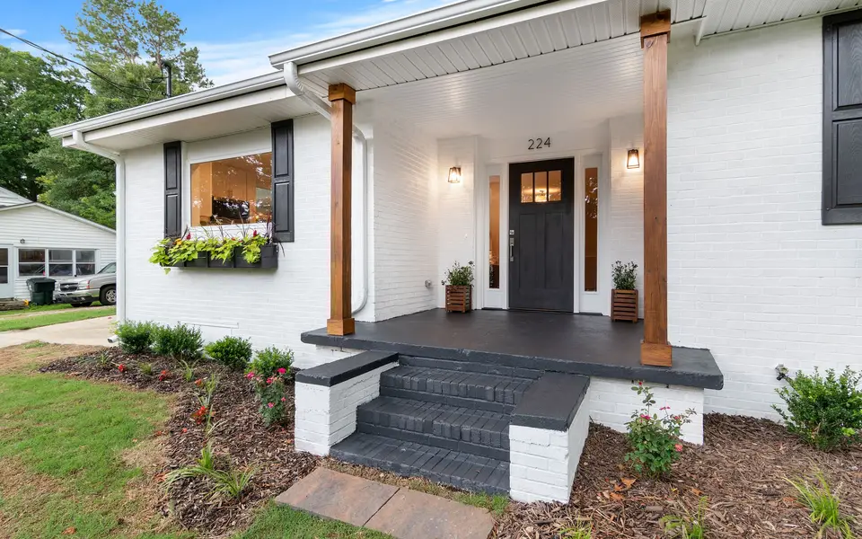 A white-brick house with a covered porch and a dark front door
