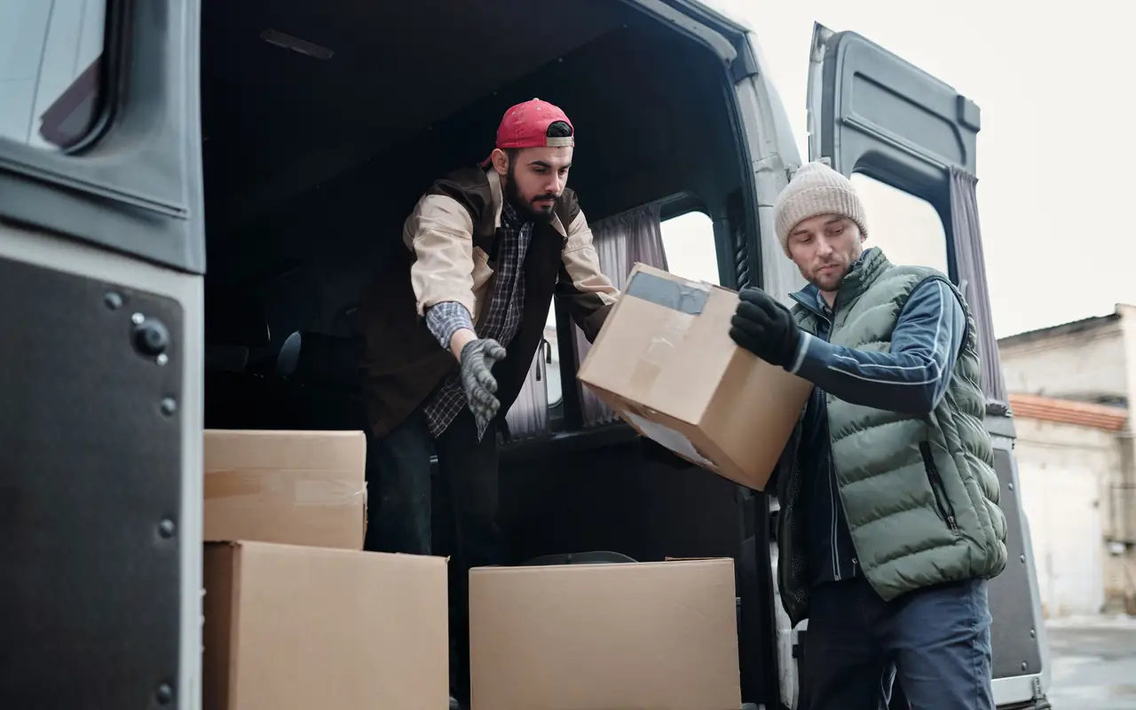 Movers carrying a wrapped sofa into a truck