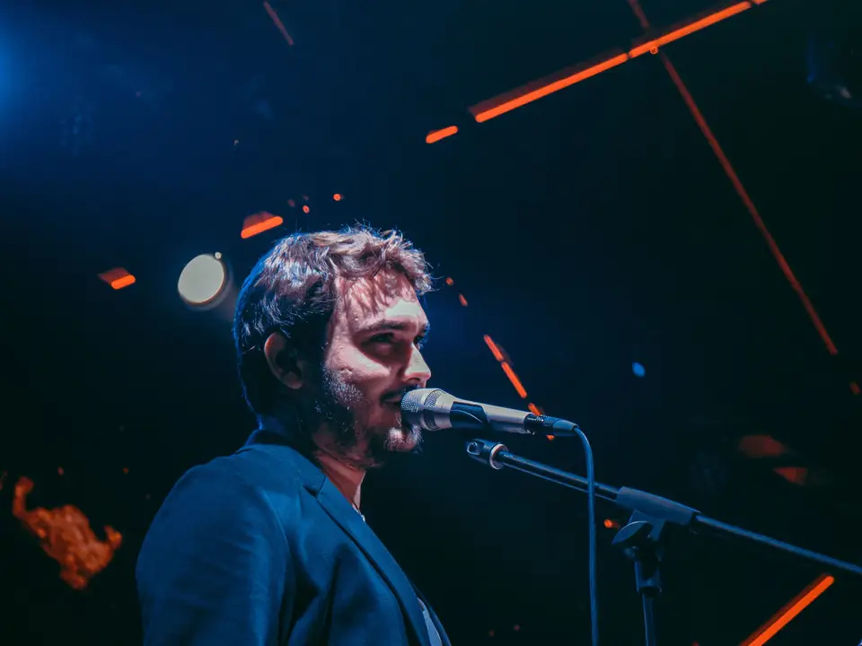 The full band on stage under blue and red lights