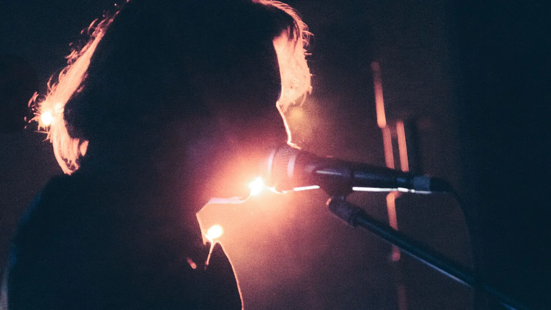 Rowan Hale at the microphone with warm stage backlight