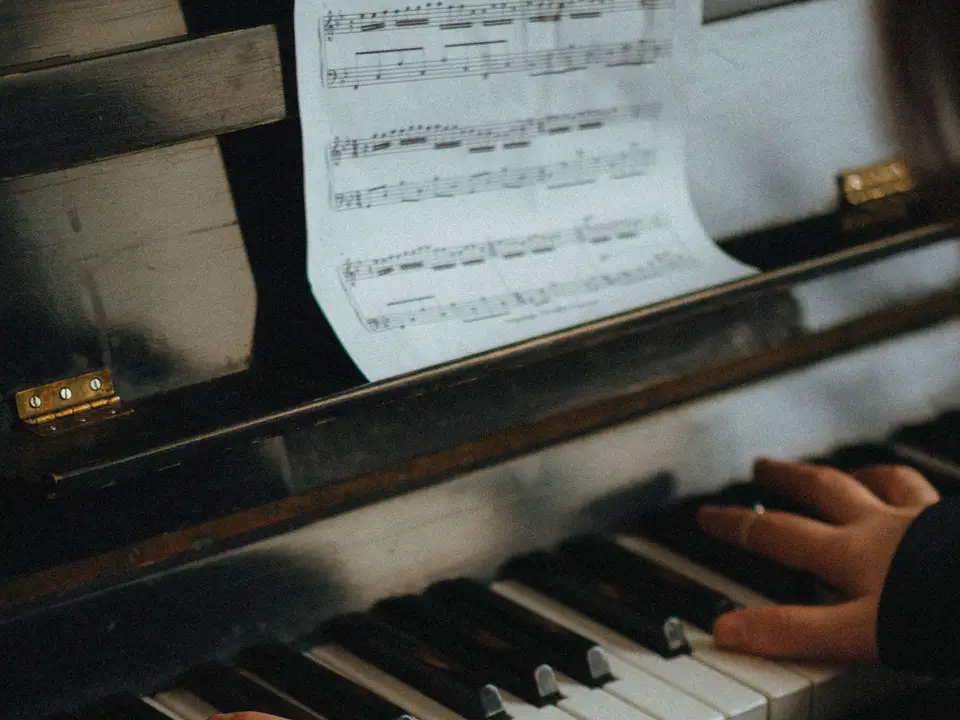 Hands playing piano with sheet music in view