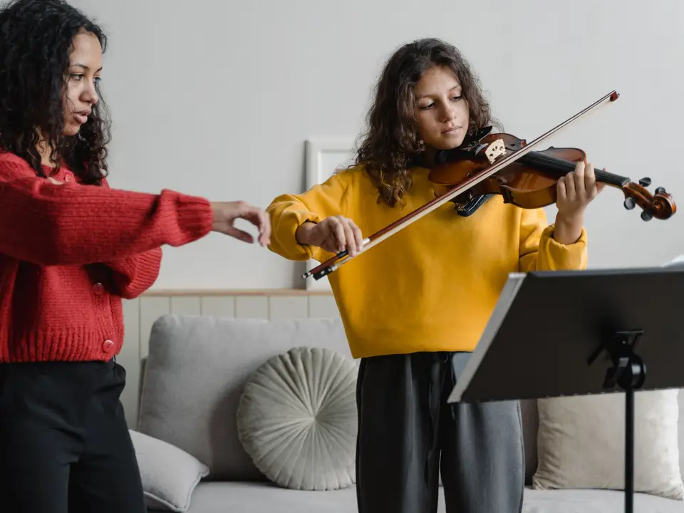Teenage girl receiving a violin lesson from an instructor
