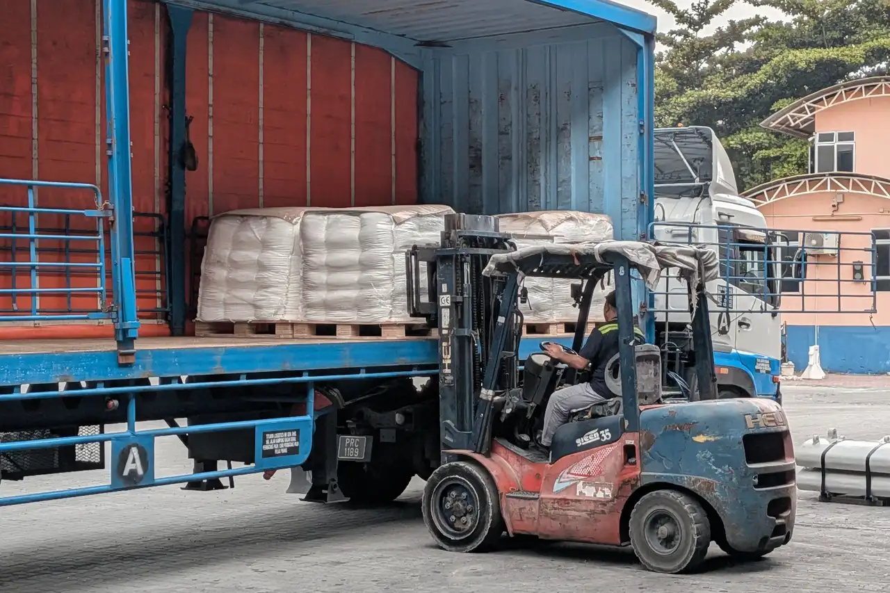 Warehouse worker holding a tablet beside stacked pallets