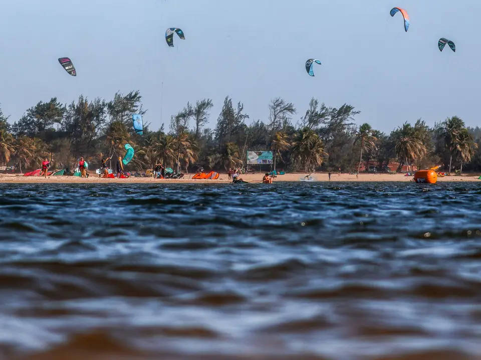 Hands unfolding a carbon kite frame on a sandy beach