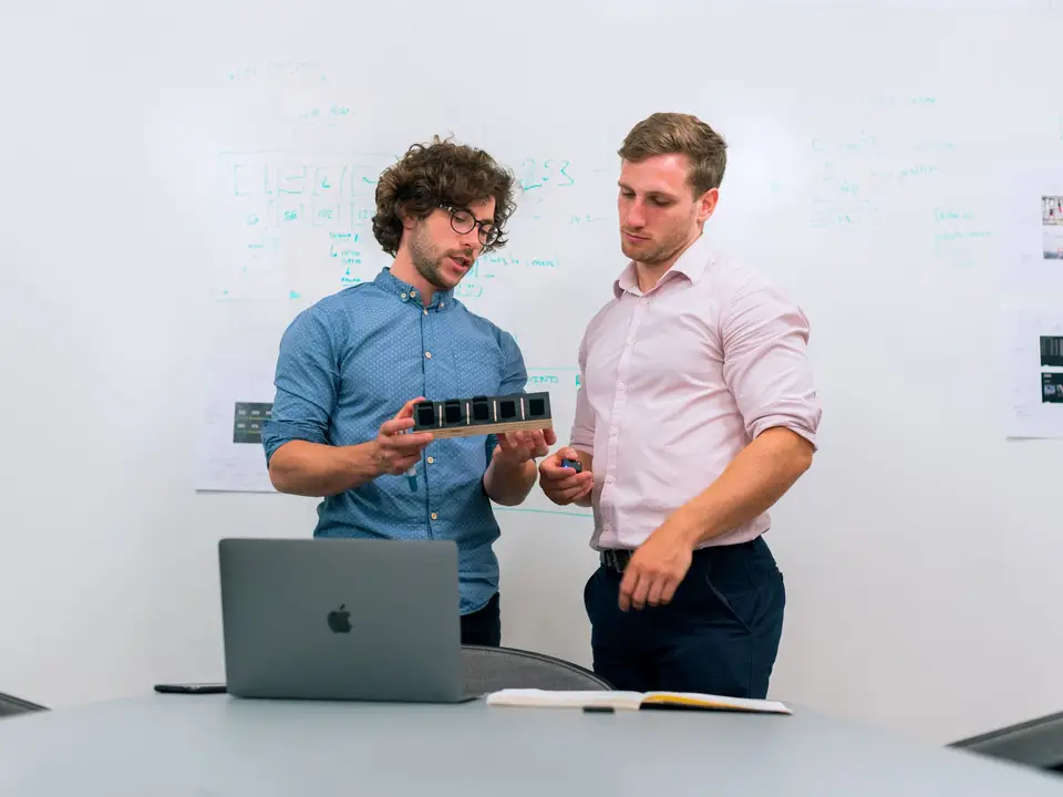 Two men reviewing a tech prototype in an office