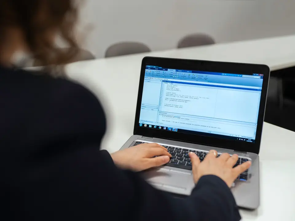 Woman coding on a laptop in a bright office