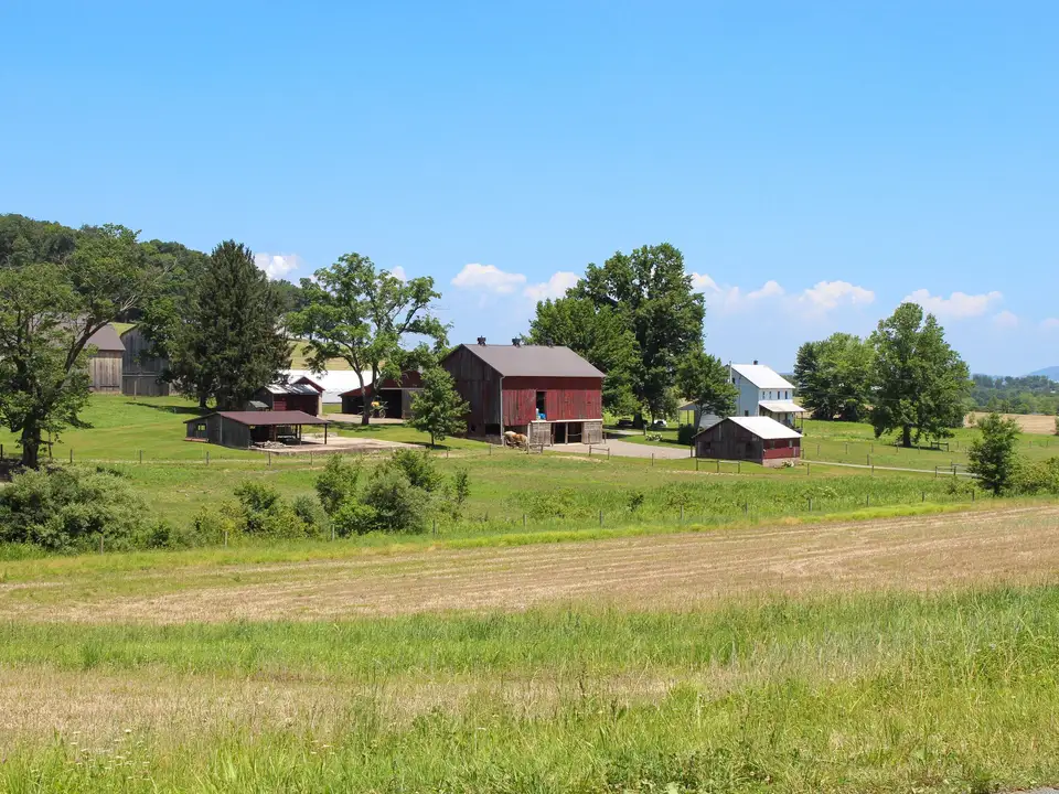 Red barn beside farm fields on a clear day