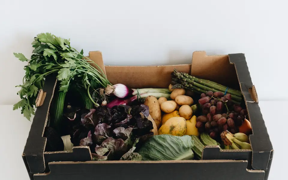 Cardboard box filled with fresh organic vegetables being prepared