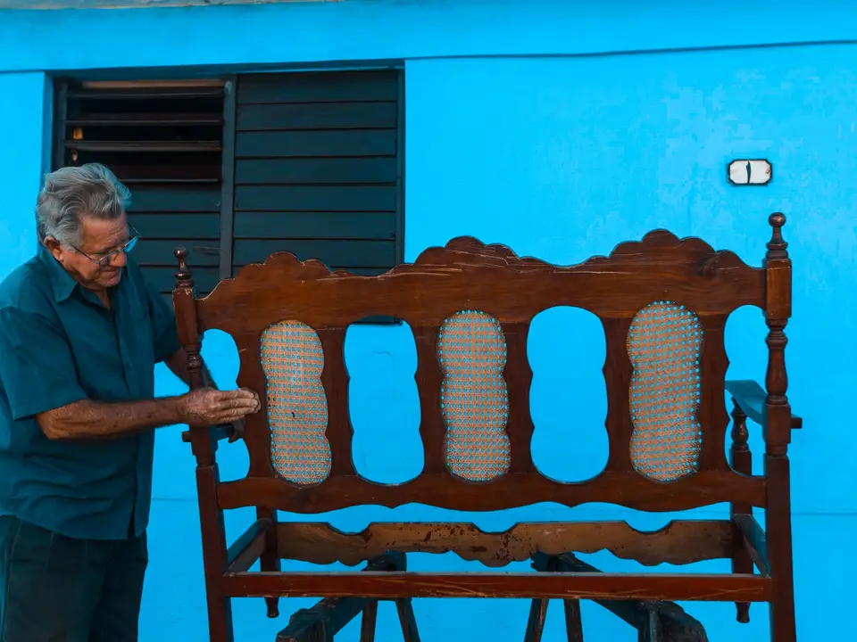 Craftsman restoring an old wooden bench