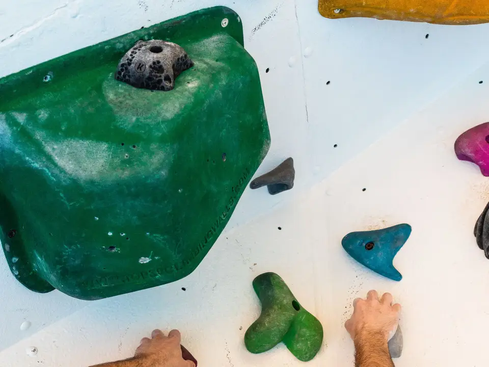 Climber reaching for holds on an indoor bouldering wall.
