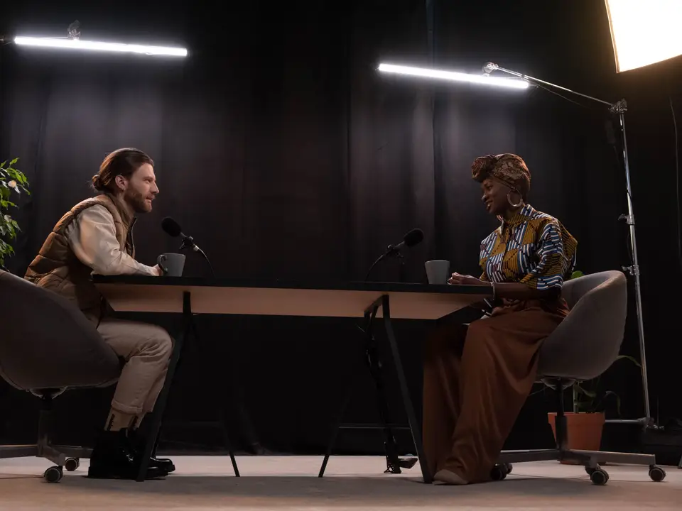 Two hosts recording a guest across a studio table
