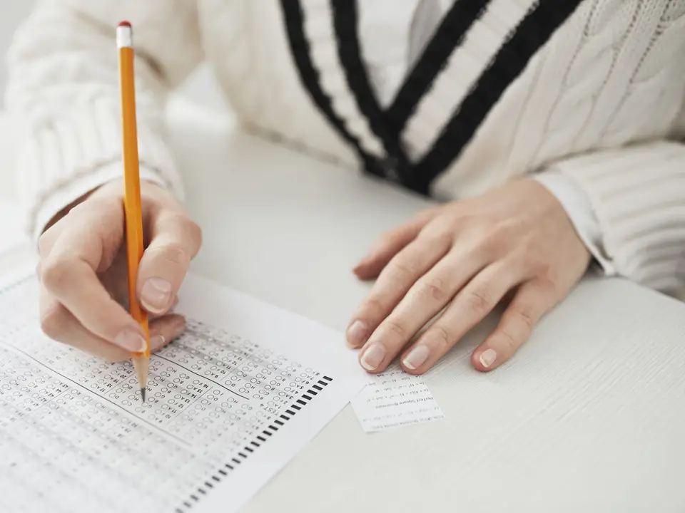 Student writing answers on an exam sheet at a desk
