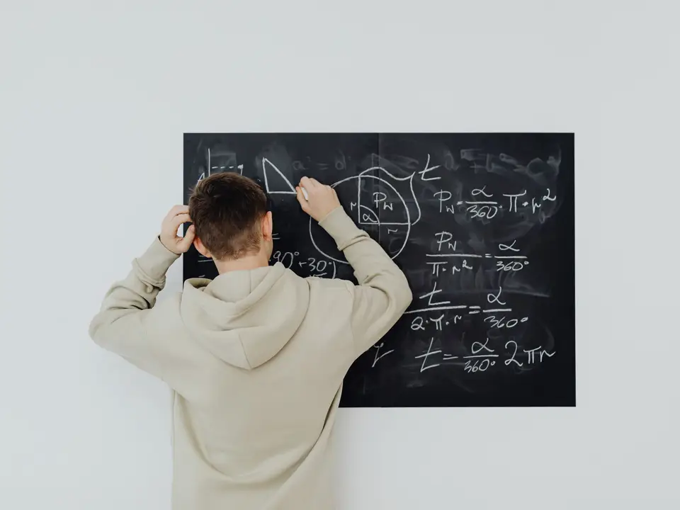 Teenager writing math formulas on a blackboard