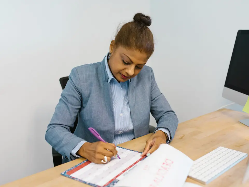 Businesswoman marking plans in a desk calendar