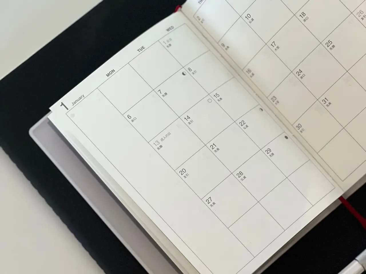 Open planner with a calendar, a pen and a tablet on a desk