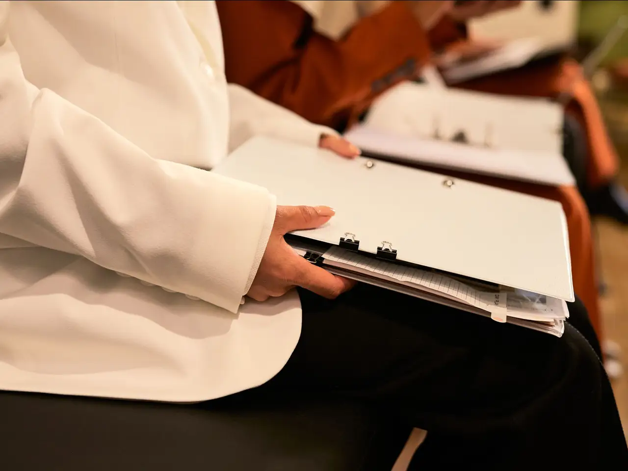 Woman holding a binder of documents in a bright office