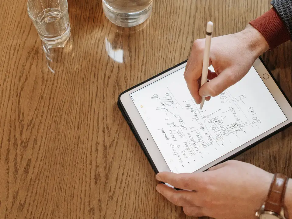 Person searching handwritten notes on a tablet at a cafe table