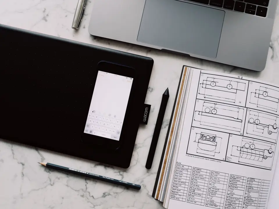 Tablet and stylus resting on a desk beside a closed laptop