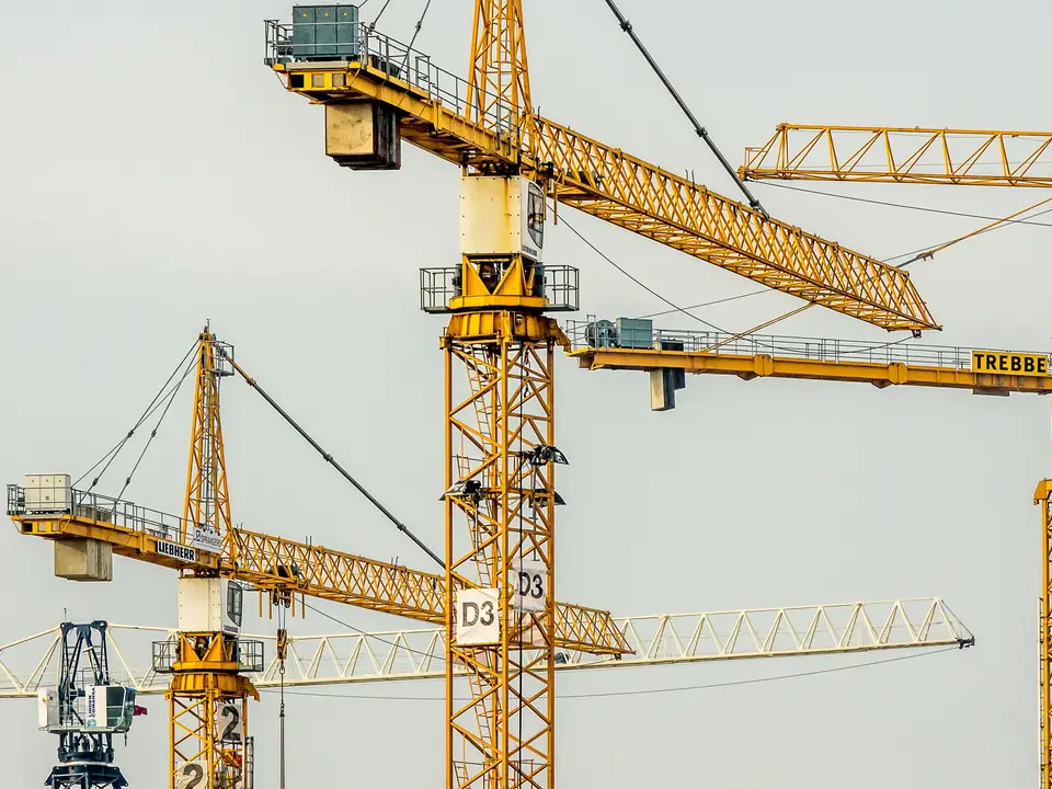 Yellow tower cranes against a pale sky