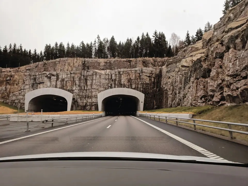 Two highway tunnel entrances cut into a rocky hillside