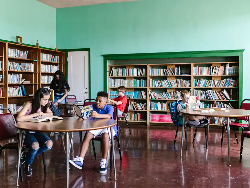 Children reading at round tables in the story room