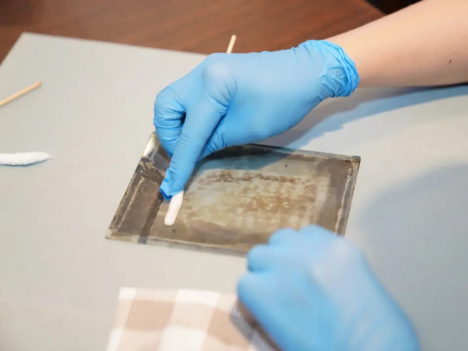 Gloved hands restoring a small ancient artefact