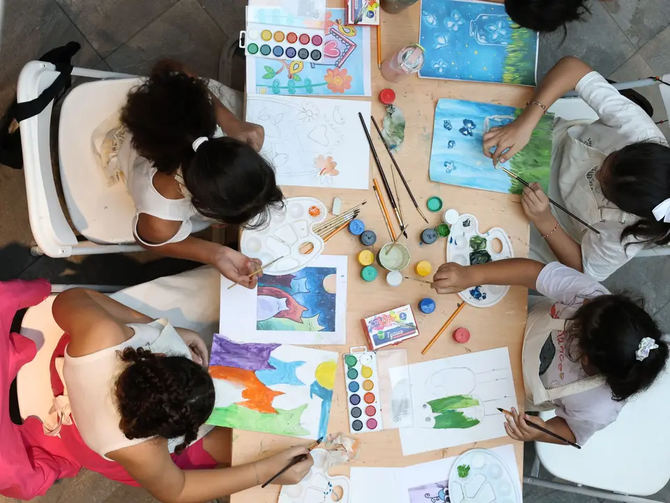 Children painting around a workshop table from above