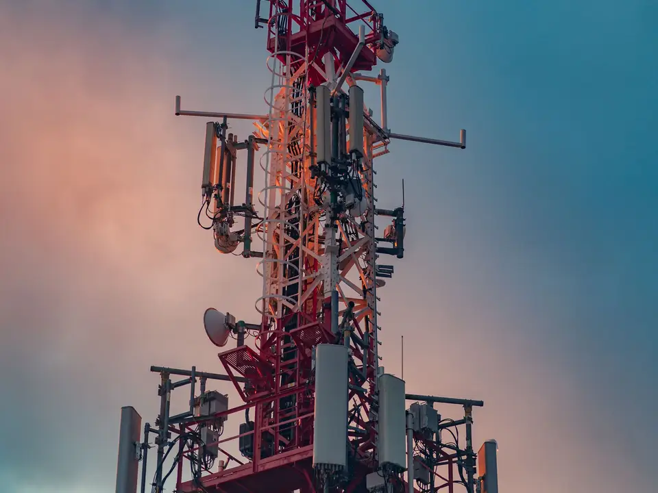 Telecommunication tower with antennas against a warm sunset sky