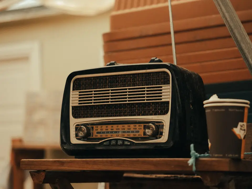 Vintage-style portable radio on a wooden table beside a coffee cup
