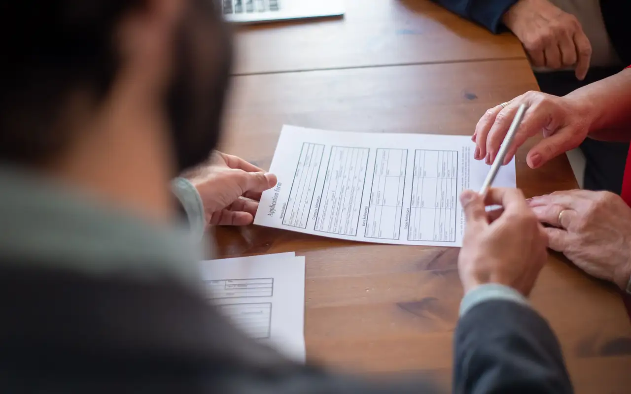 Couple reviewing listing photos with a real estate agent at a kitchen table