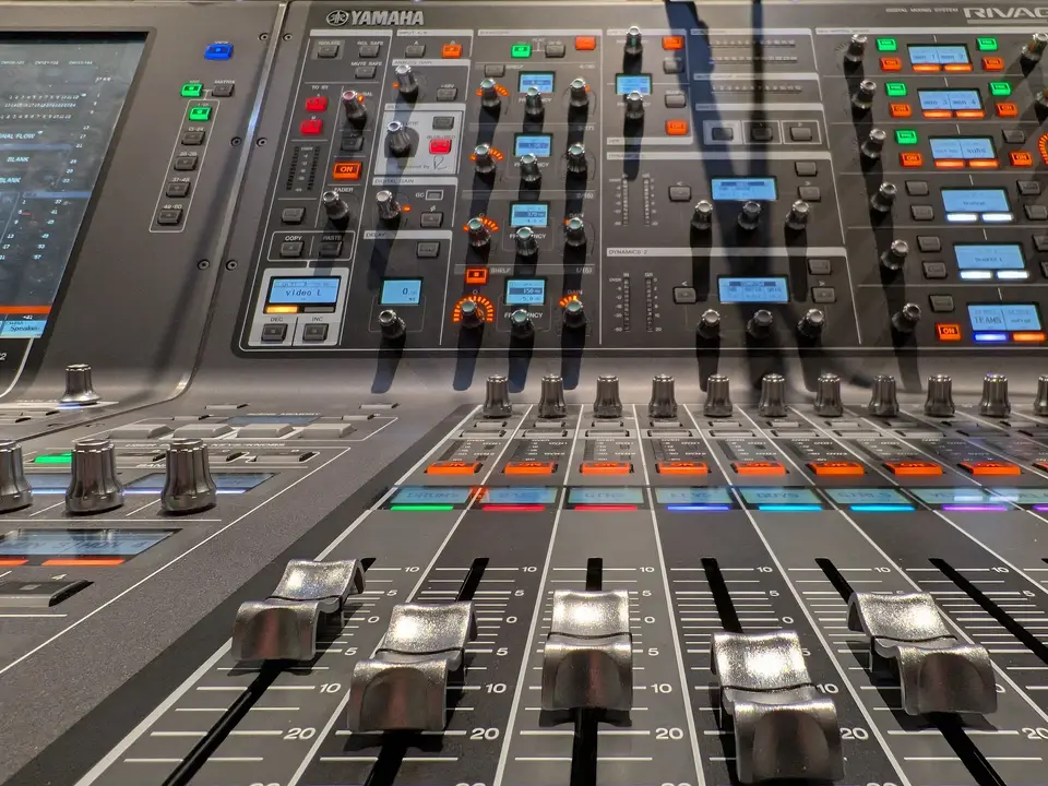 High-angle view of a large mixing console with faders and illuminated buttons