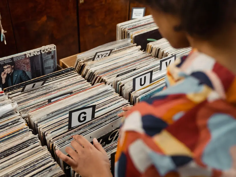 Over-the-shoulder view of someone flipping through alphabetised vinyl records