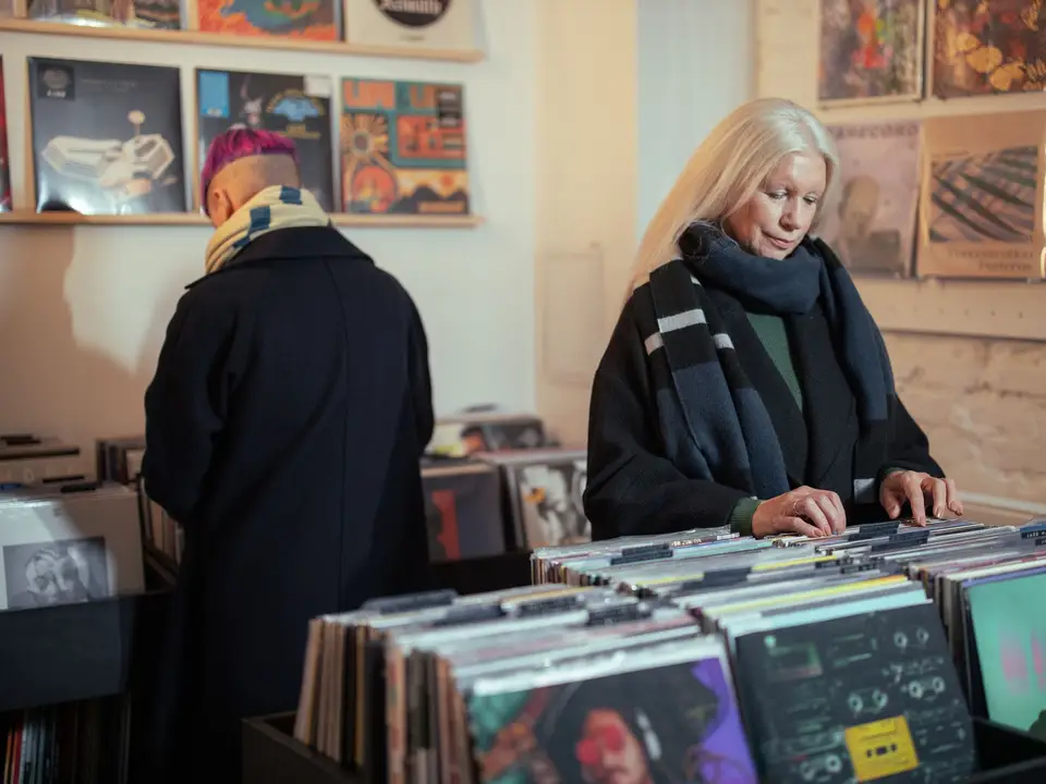 Customers browsing vinyl in a record shop with records on a white brick wall