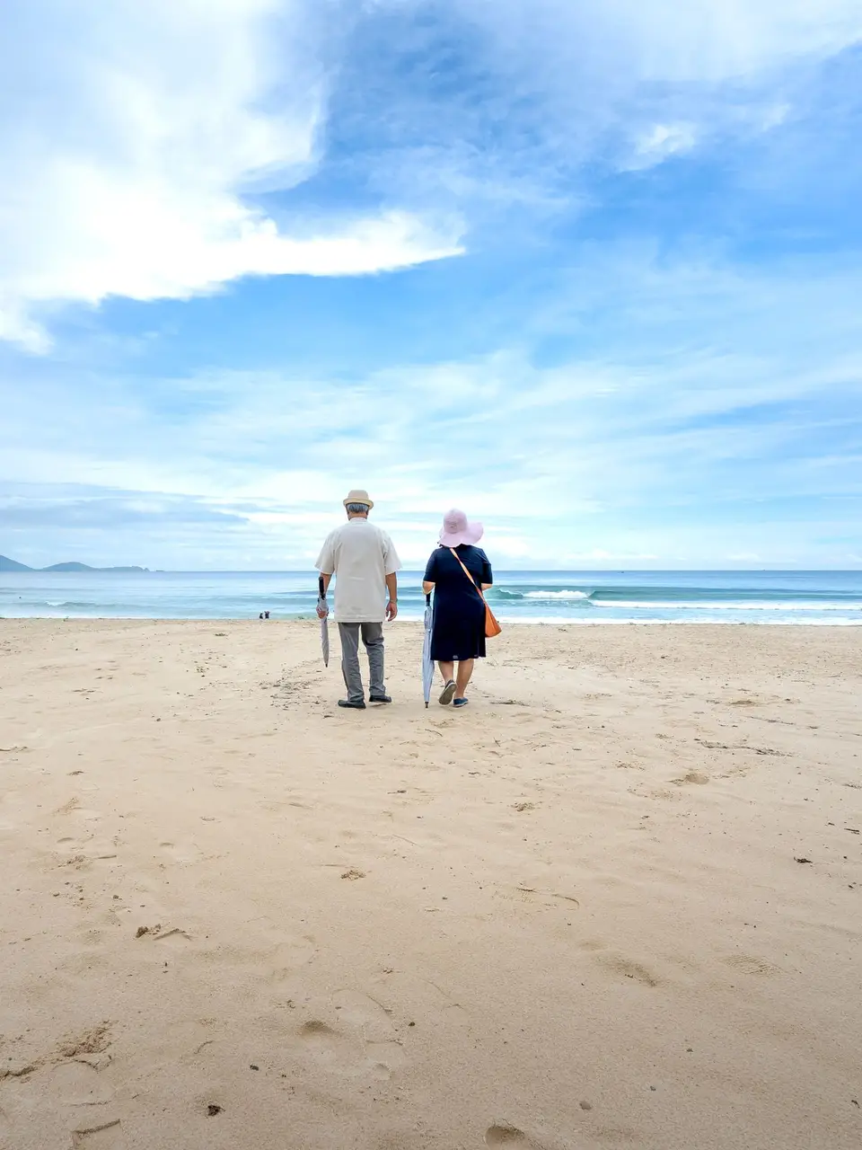 A senior couple walking along a wide sandy beach