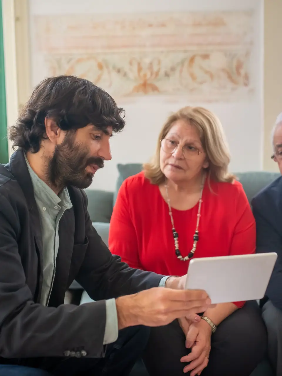 An adviser showing an elderly couple options on a tablet in their living room