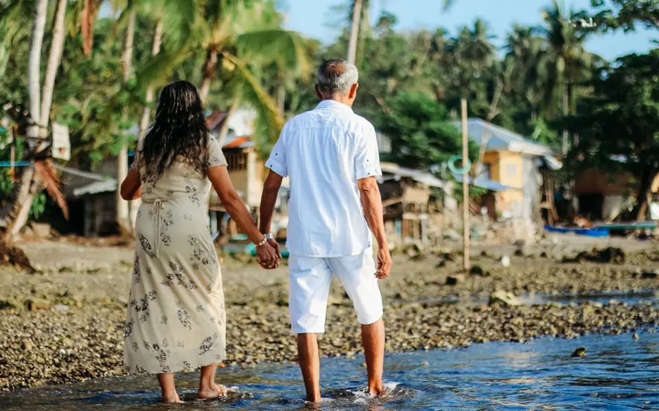 A senior couple holding hands on a shoreline