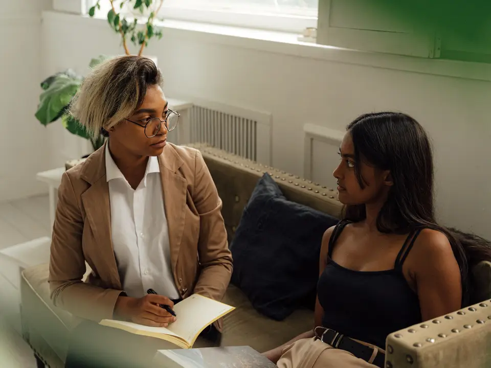 Two women engaged in a counseling session indoors, promoting dialogue and learning