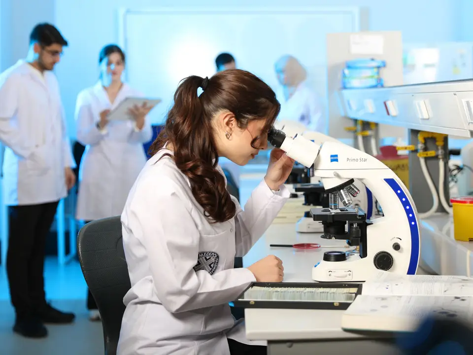 Young female scientist examining samples under a microscope in a modern laboratory setting