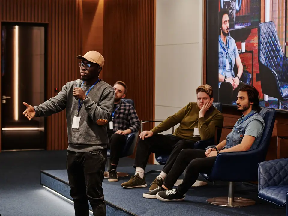 Speaker with a microphone addressing a seated audience at a panel event