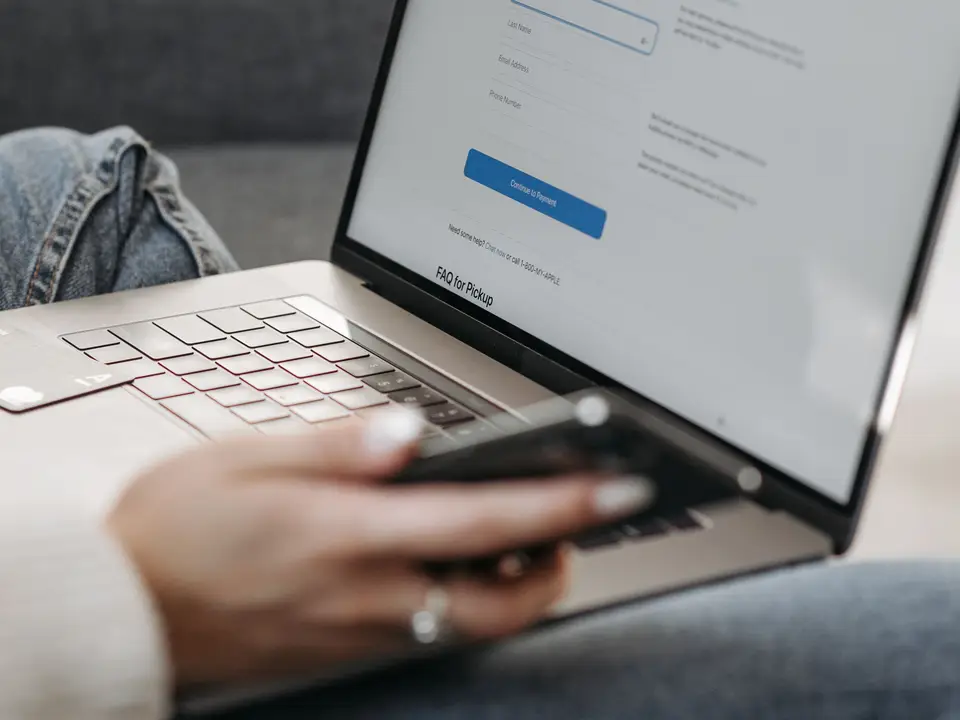 Person checking a laptop and smartphone together