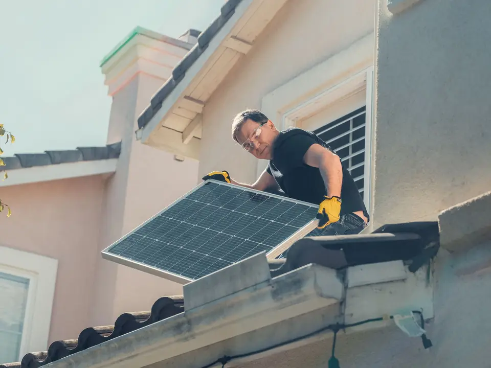 Technician holding solar panels on a barn roof