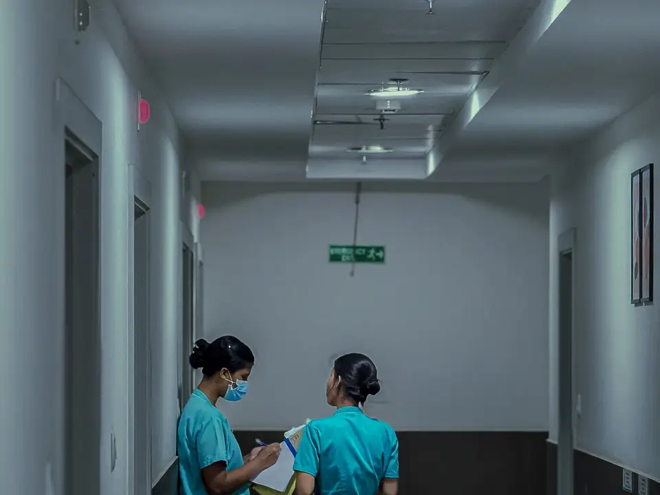 Two nurses reviewing notes in a hospital corridor