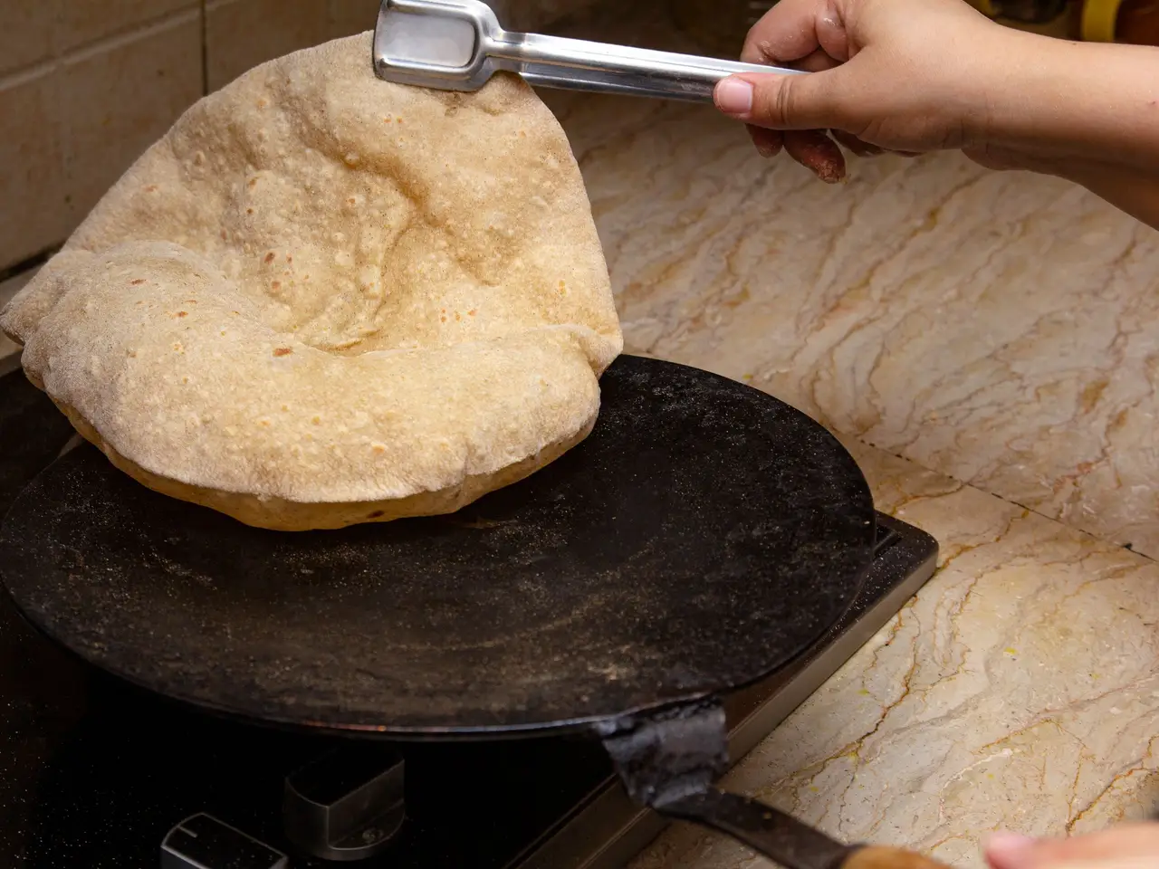 Fresh rotis stacked beside a tawa on a highway dhaba counter
