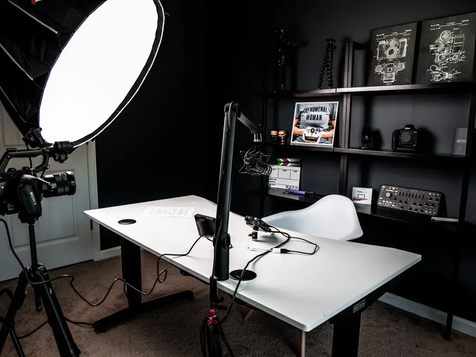 Bright streaming desk with a microphone, ring light and media shelves