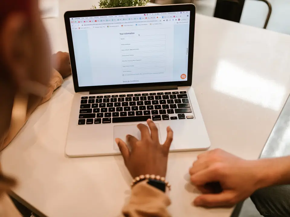Two adults filling out an online form on a laptop