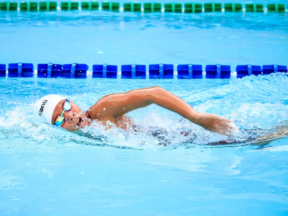 Swimming goggles and towel on bench